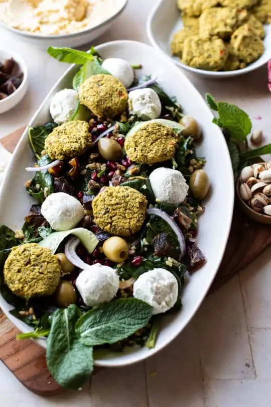 Serving plate with bulgur falafel salad and labneh balls.