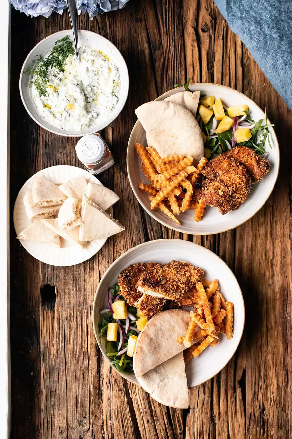 Two plates with crispy chicken with Panko breading, tzatziki on the side.