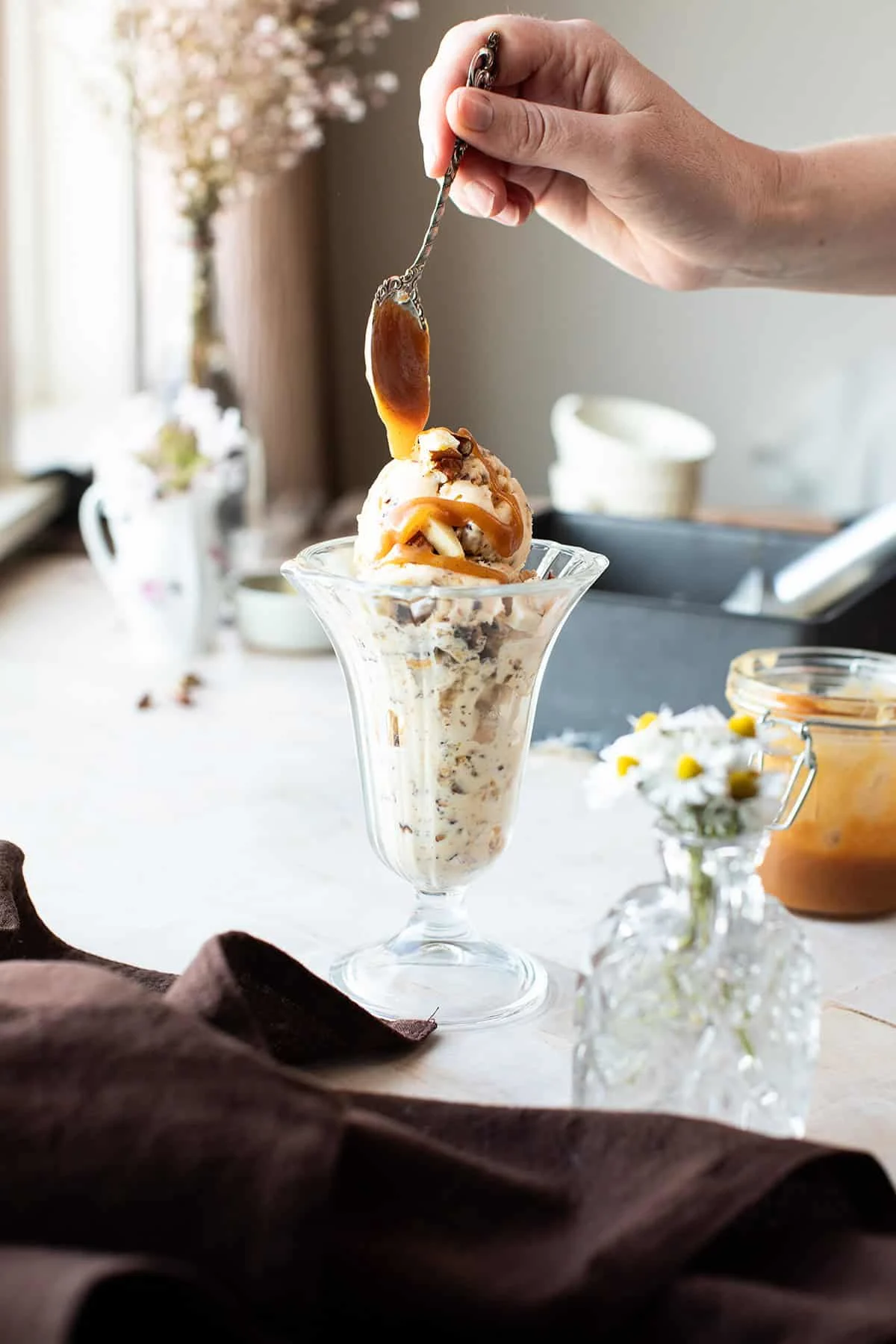 Drizzling salted caramel on top of a serving of roasted pecan ice cream.