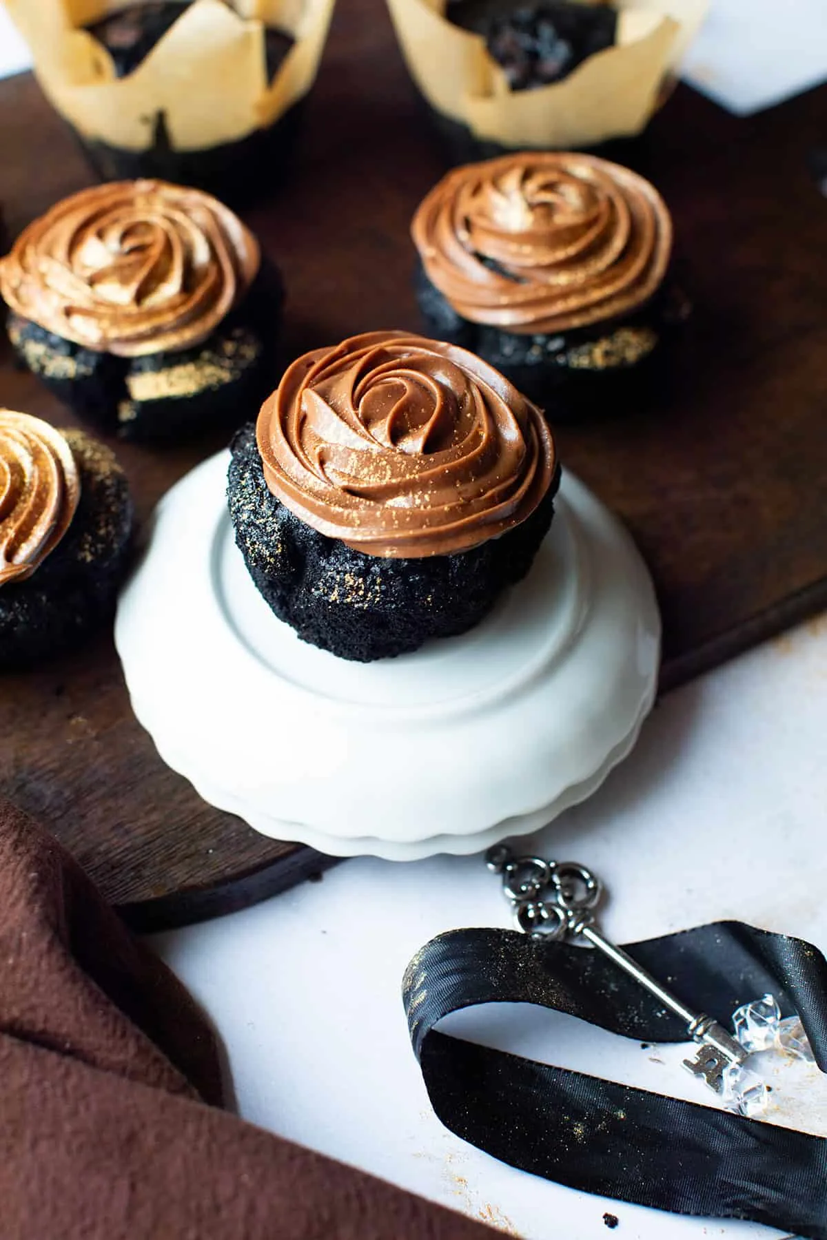 Chocolate fudge cupcakes on a stack of white plates.