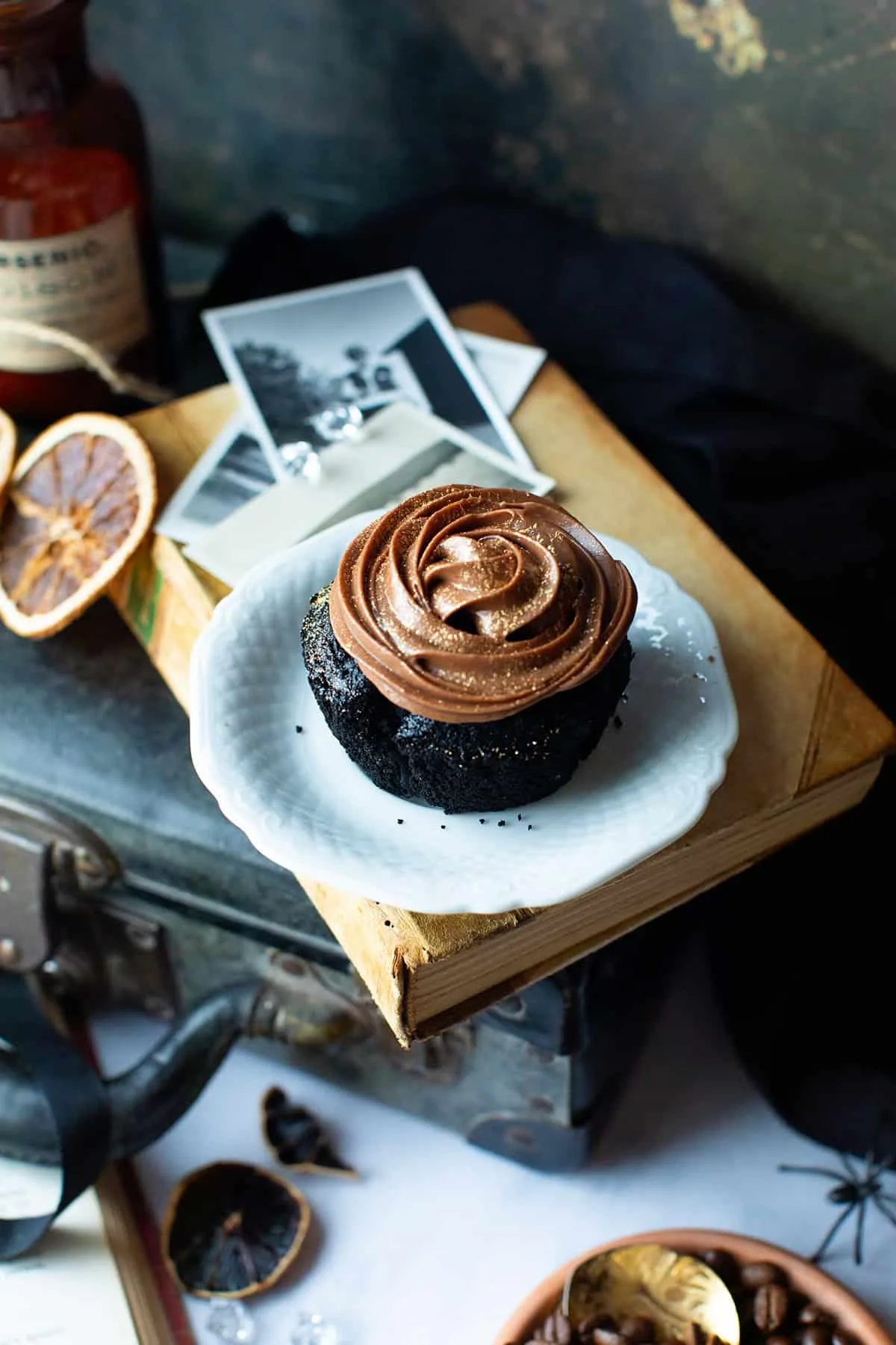 Dark chcoolate fudge cupcakes on a white plate on a vintage book.