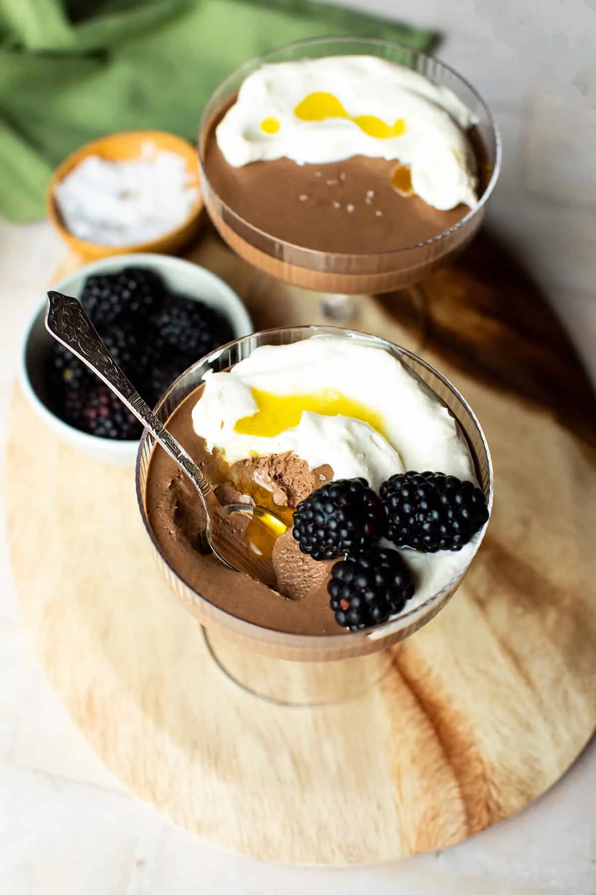 Glass with chocolate mousse and olive oil dripping into where a bite was taken out of it.