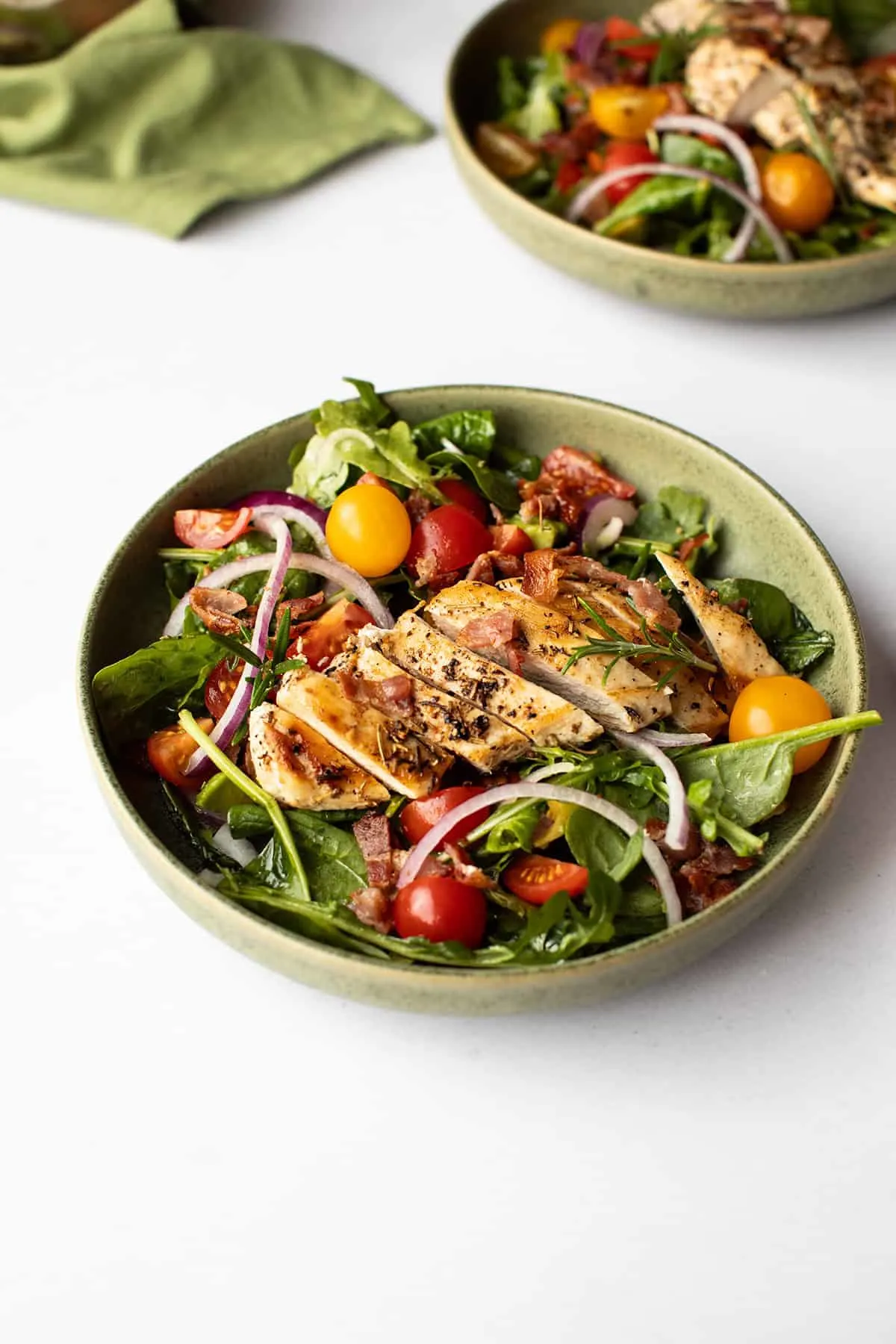 Grilled chicken and bacon salad in a green bowl.