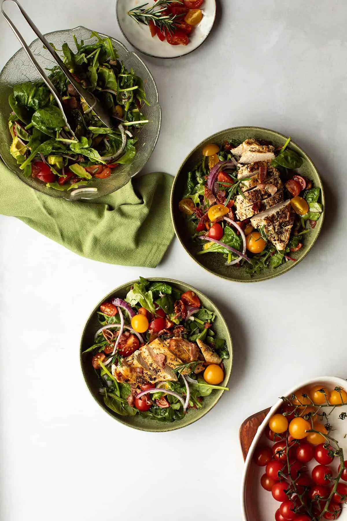 Two green bowls with chicken and tomato salad.