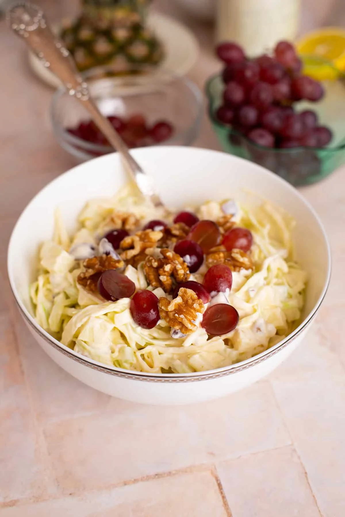 Serving bowl with Waldrof salad garnished with grapes and walnuts.
