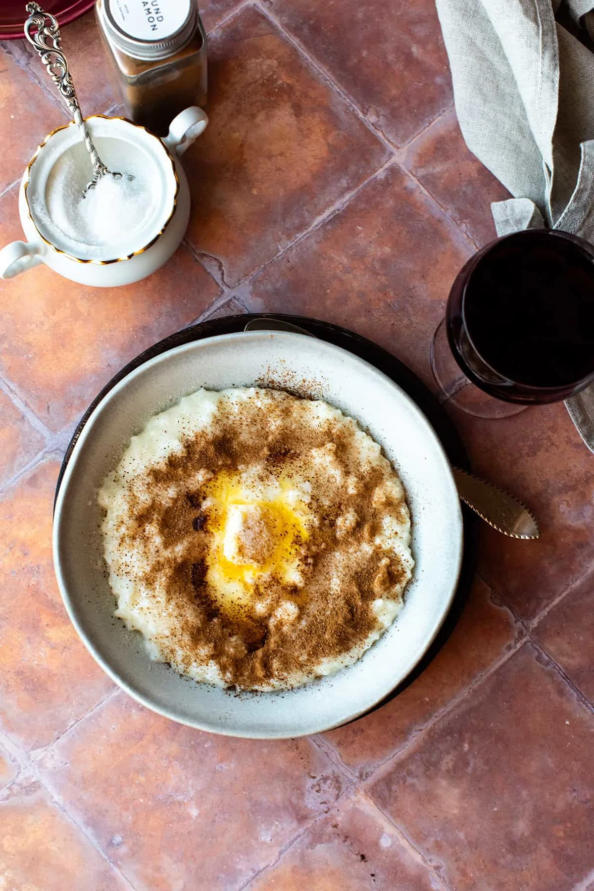 A serving bowl of Norwegian rice porridge with cinnamon, sugar and melted butter on top.