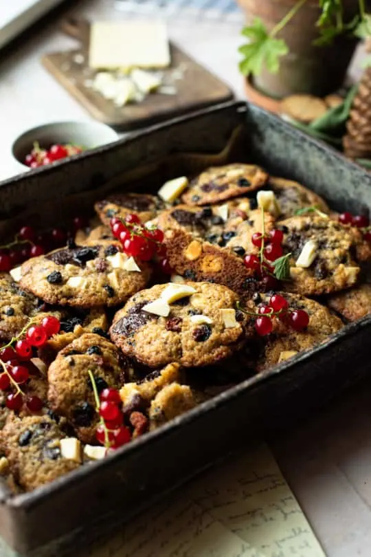 Metal tray with dried berries cookies and garnished with fresh red currants.