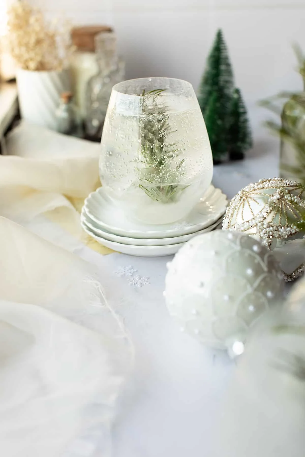 Clear cocktail with a rosemary tree in the middle to look like a snow globe.