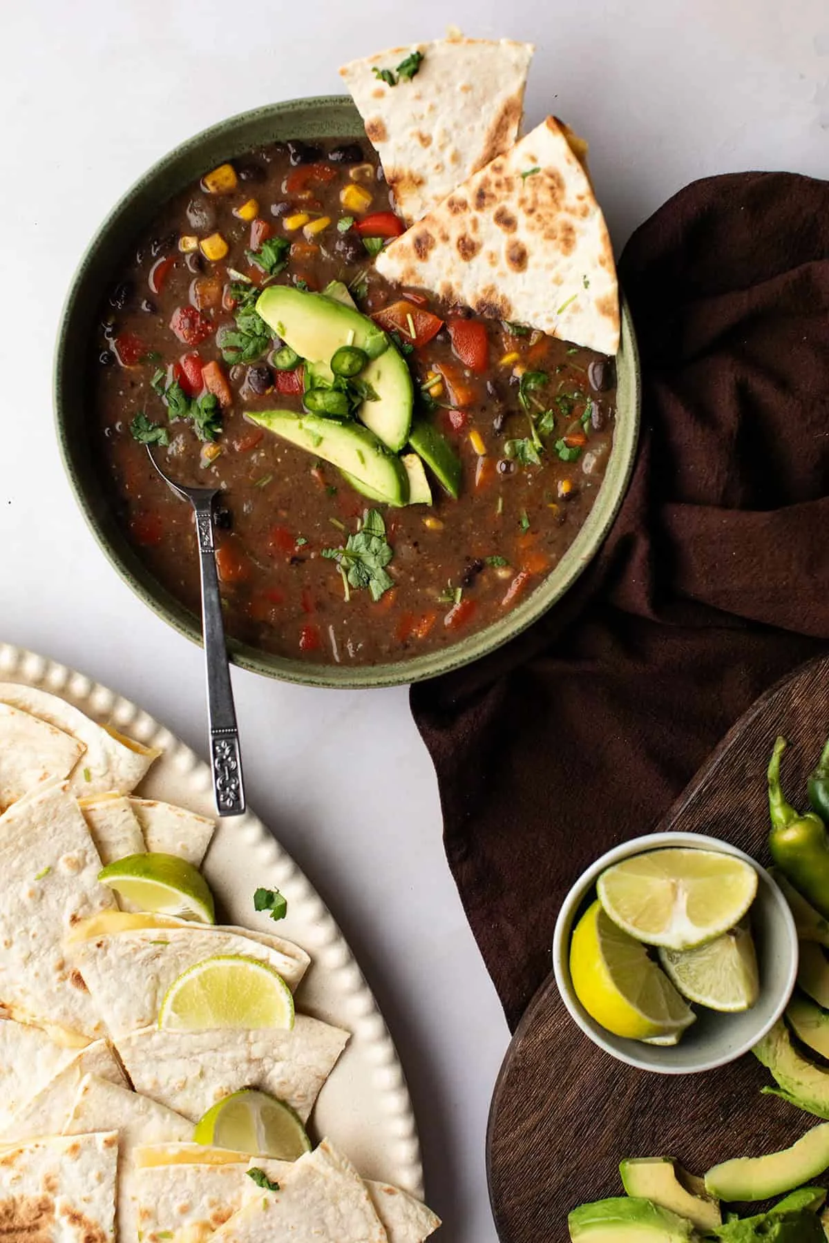 One green bowl with spicy black bean soup with avocado and quesadillas.