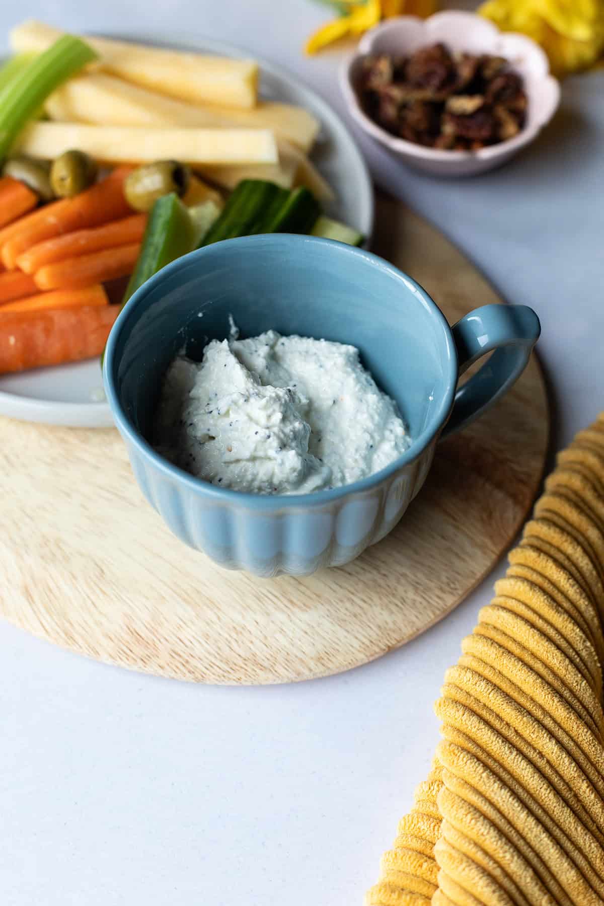 Blue cup with cottage cheese dip and a tray of vegetable sticks.