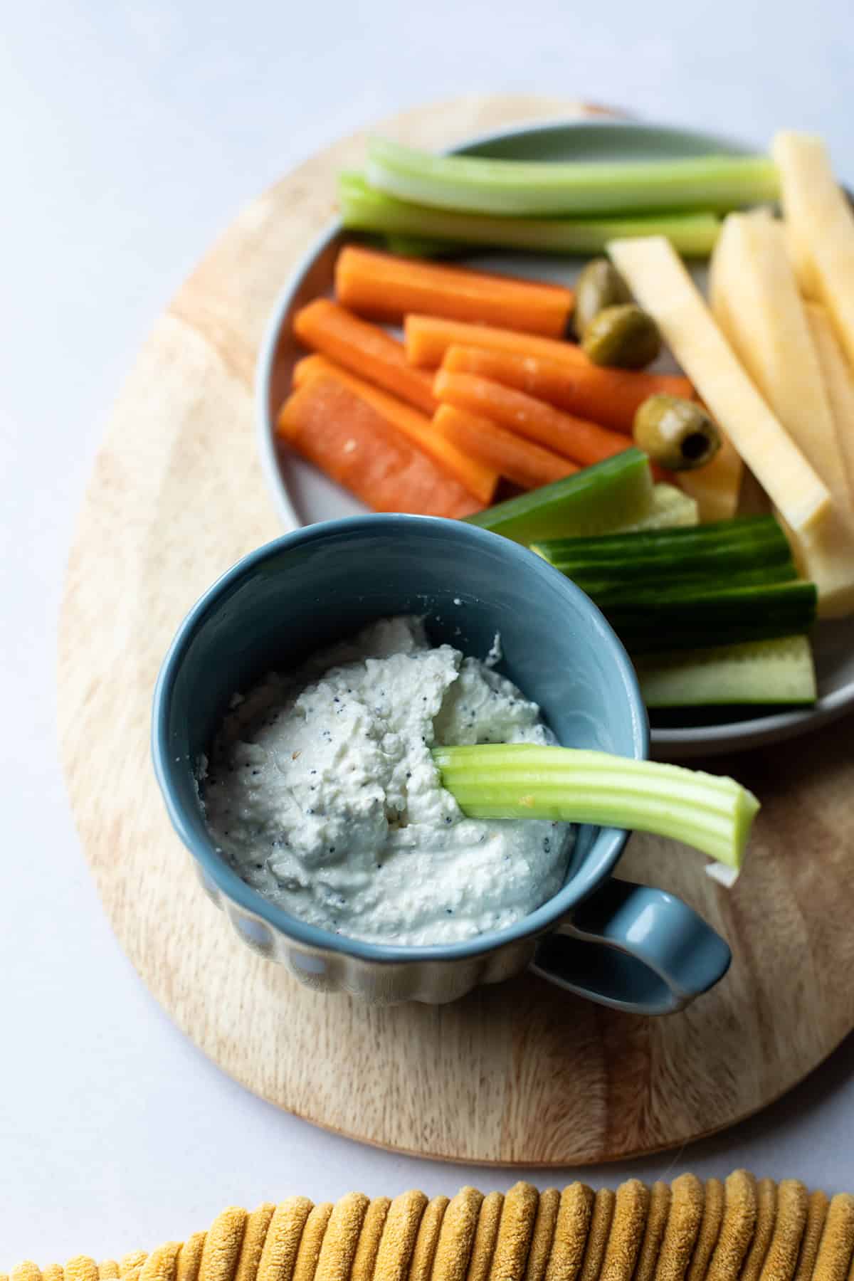 Blue mug with cottage cheese ranch dip and a stick of celery.