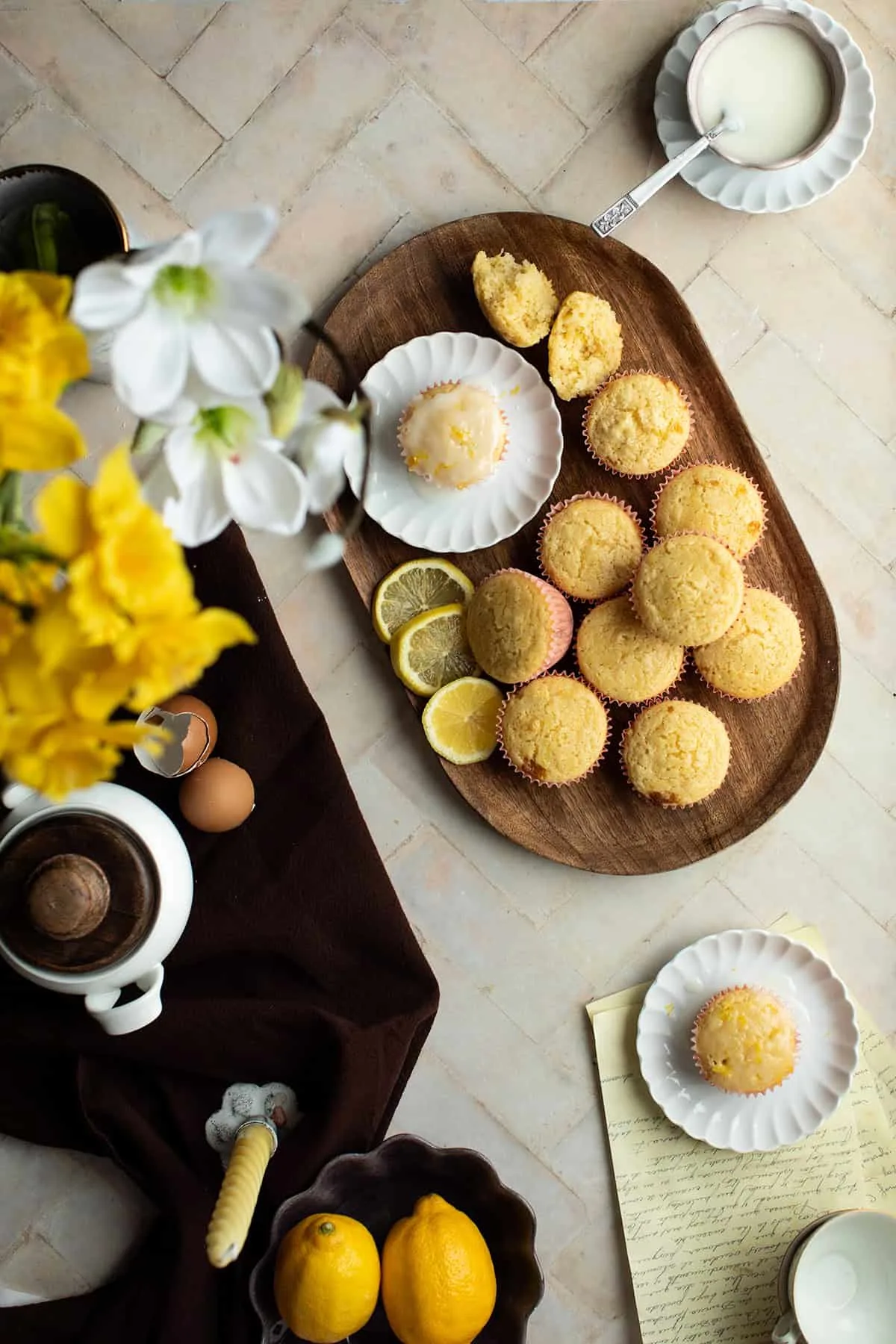 Lemon muffins with no glazing on a wooden plate. One glazed on a white plate.