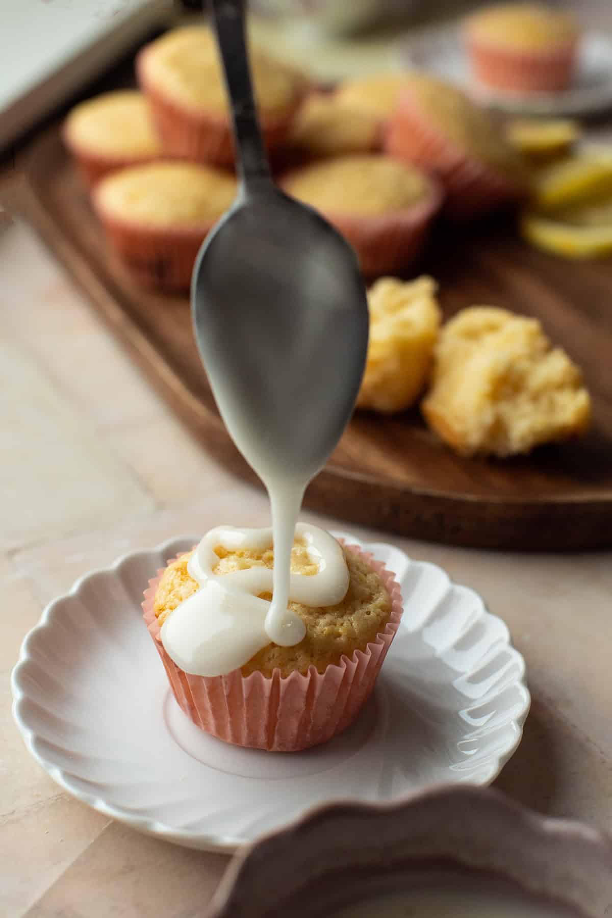 Pouring a lemon drizzle on top of a muffin.