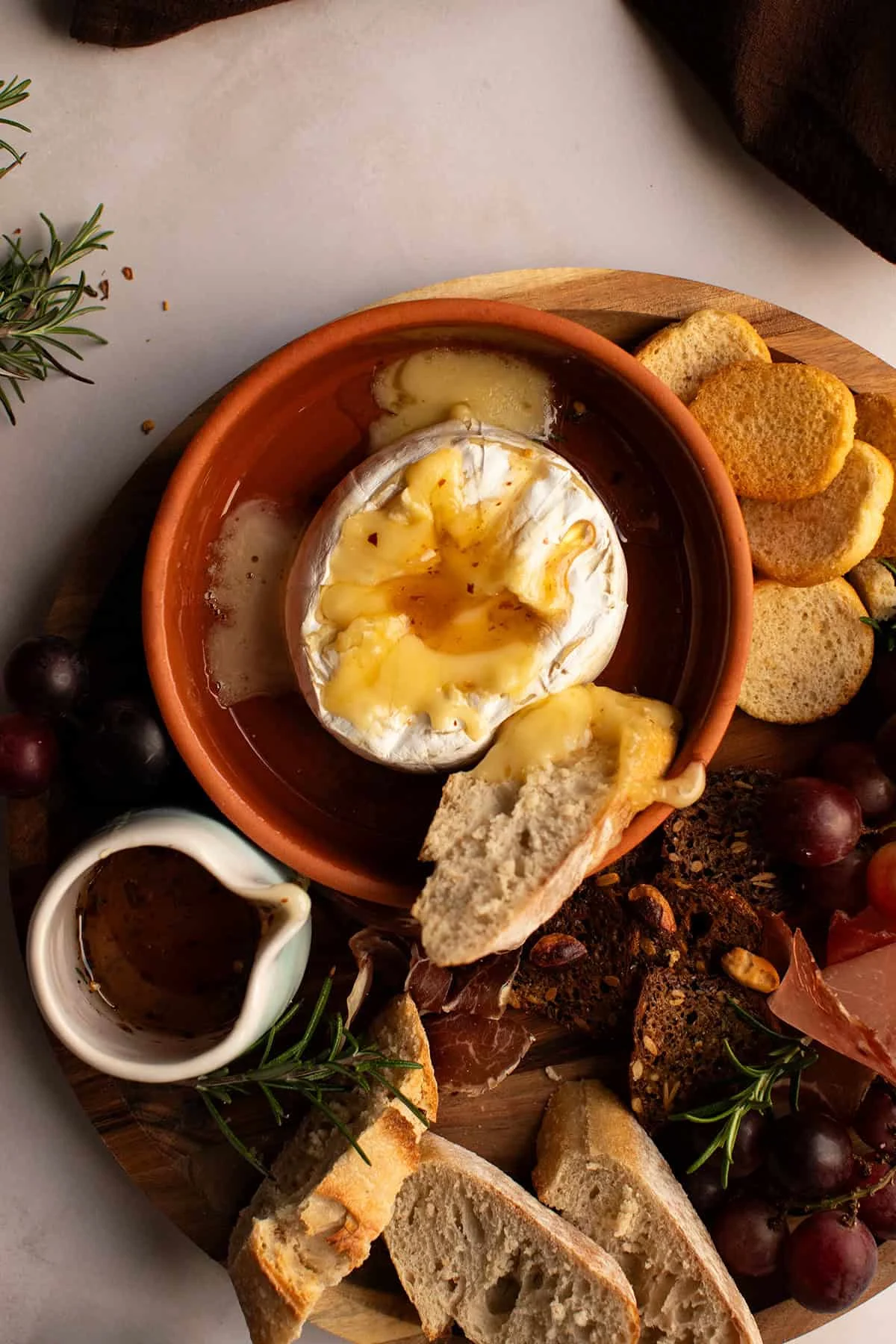 Hot honey brie on a tray with grapes and bread.