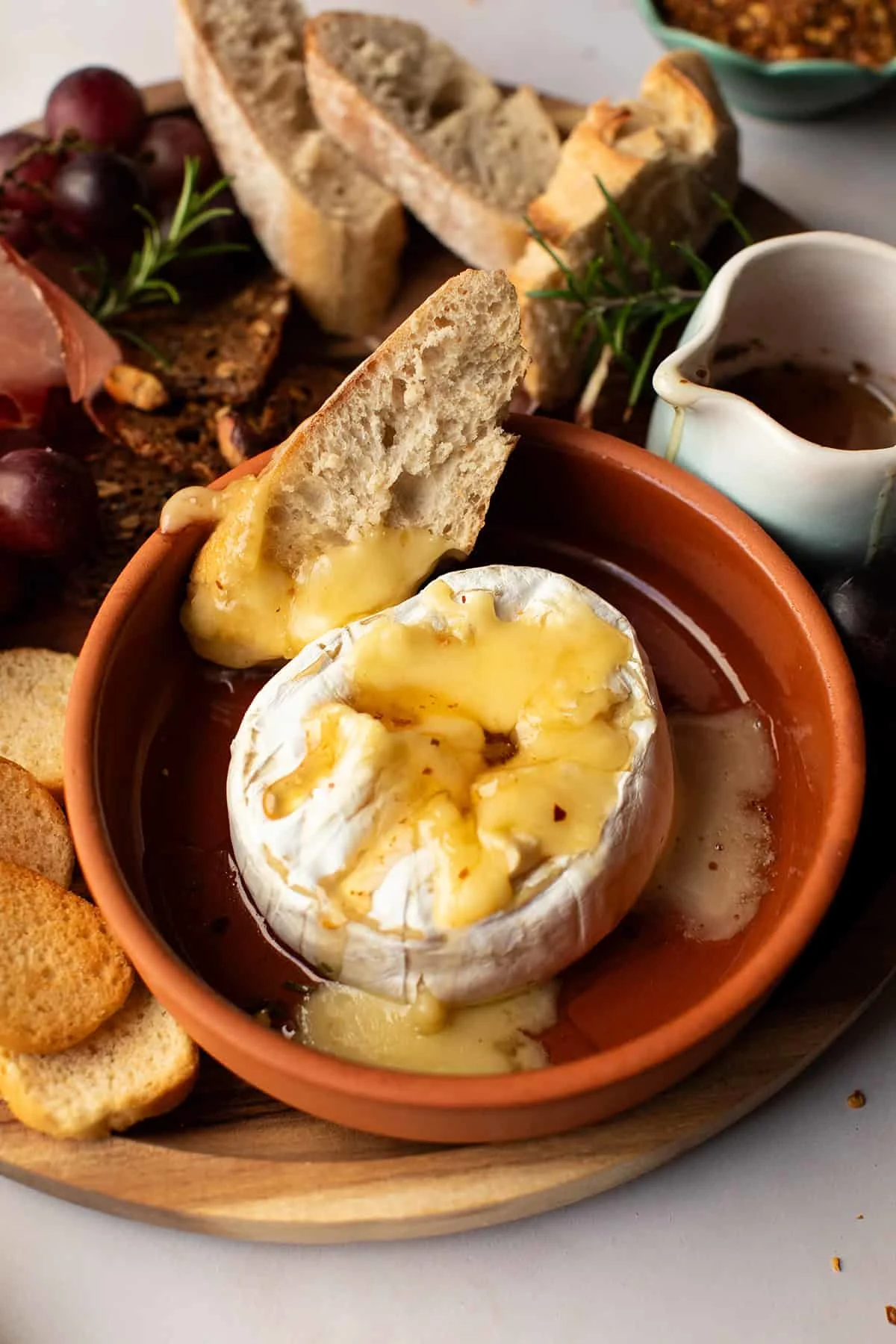 Close-up of the baked brie with a slice of bread in the background.