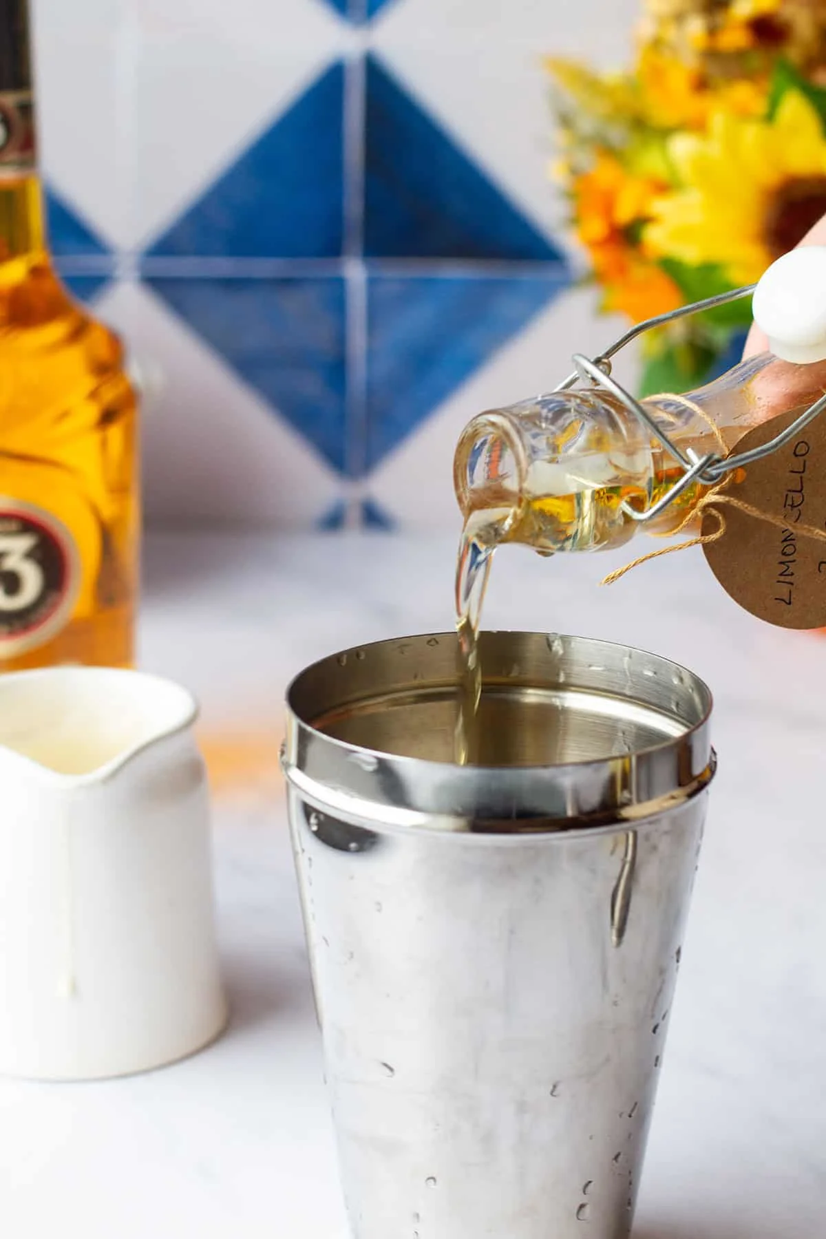 Pouring limoncello in a cocktail shaker.