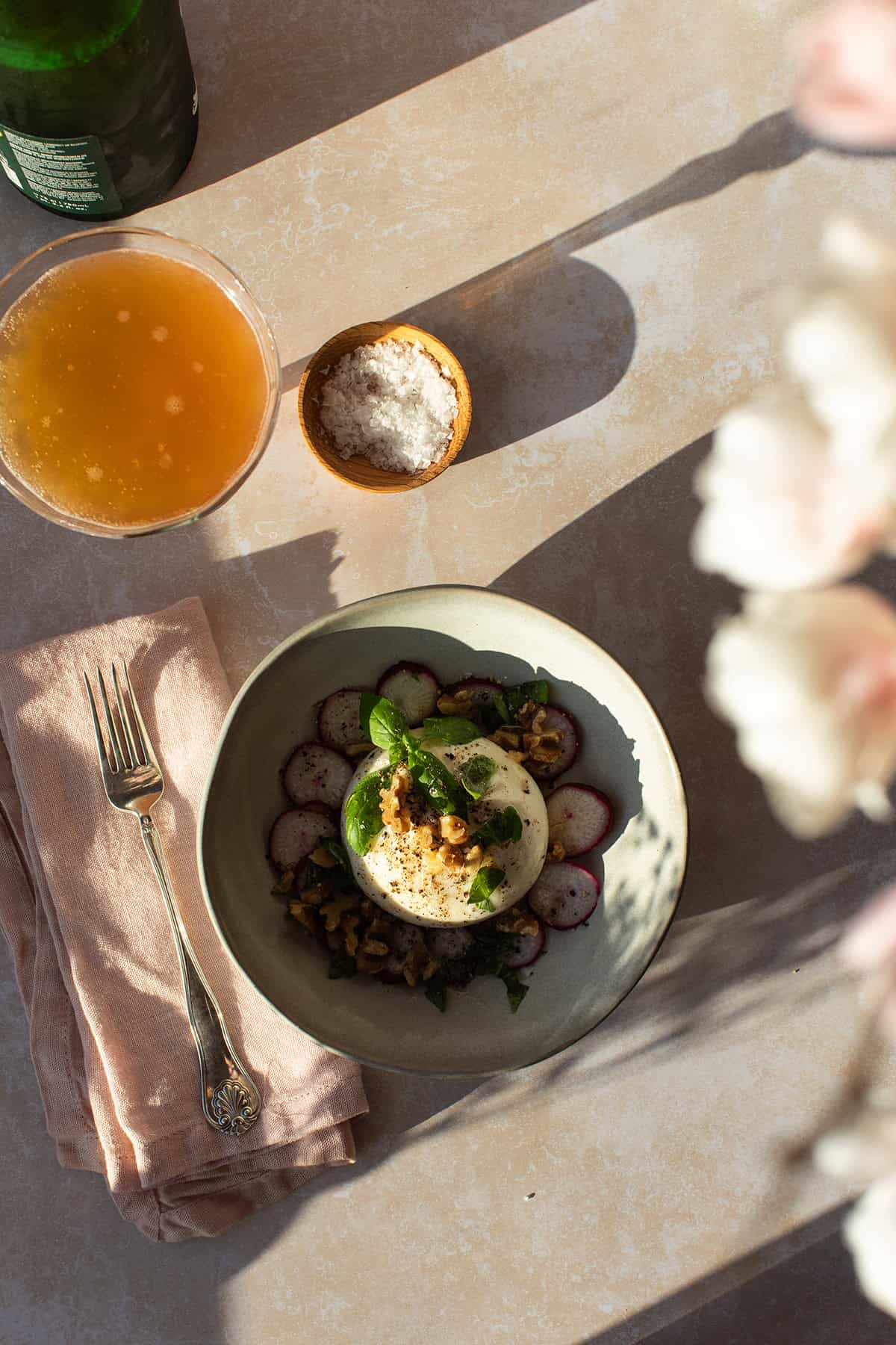 Bird's eye view of a bowl with burrata, radishes and fresh basil.