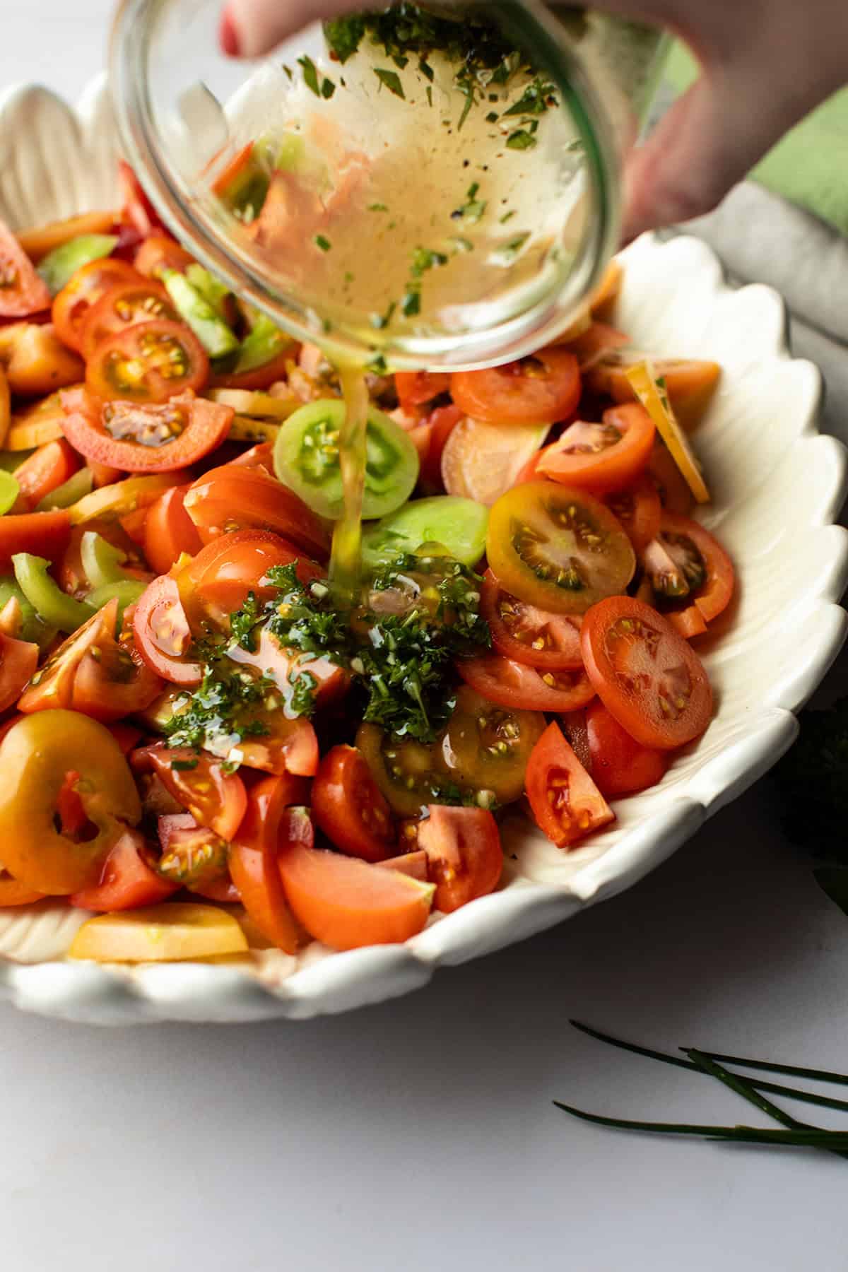 Pouring dressing over sliced tomatoes.
