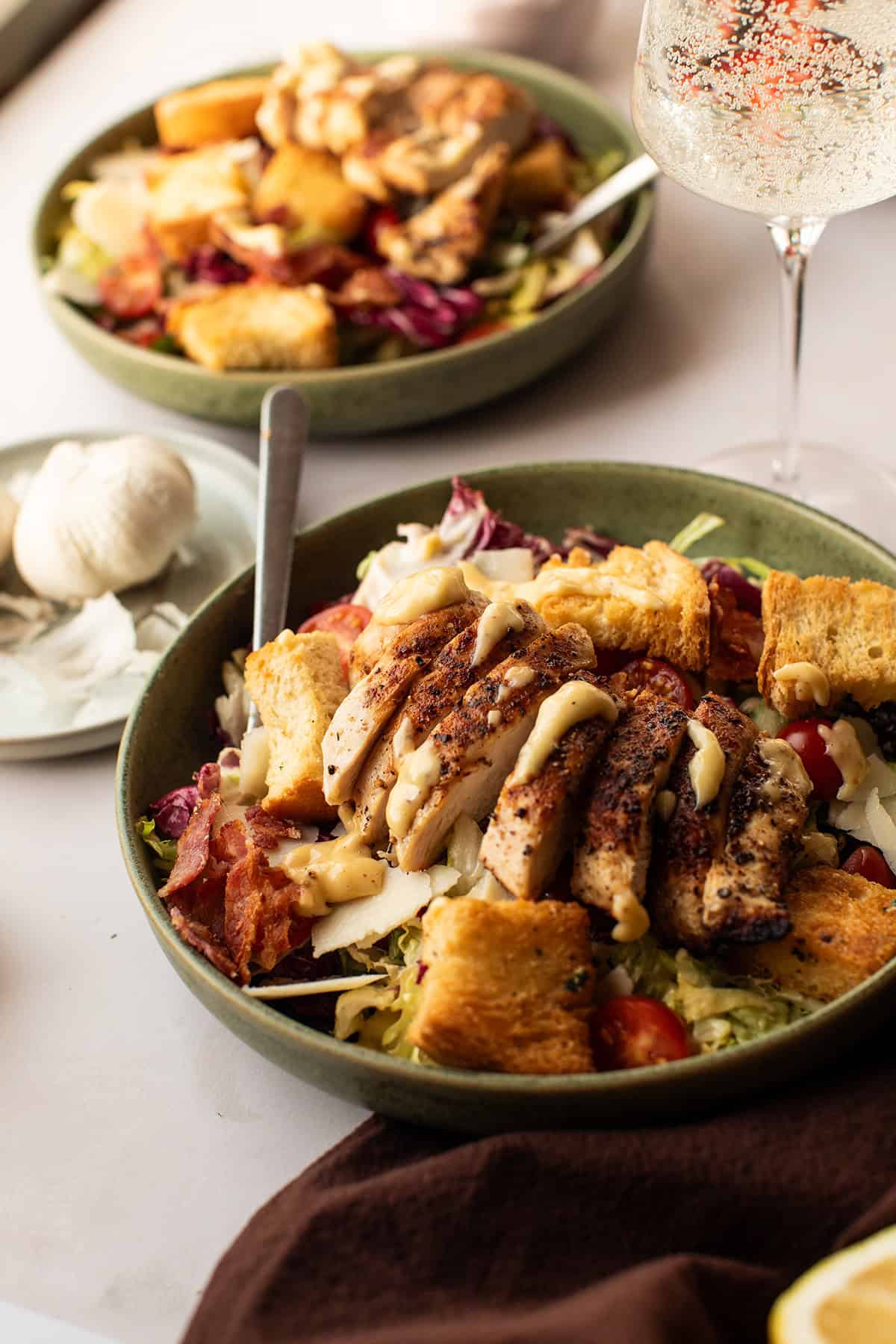 Close-up of a chicken caesar salad in a green bowl.