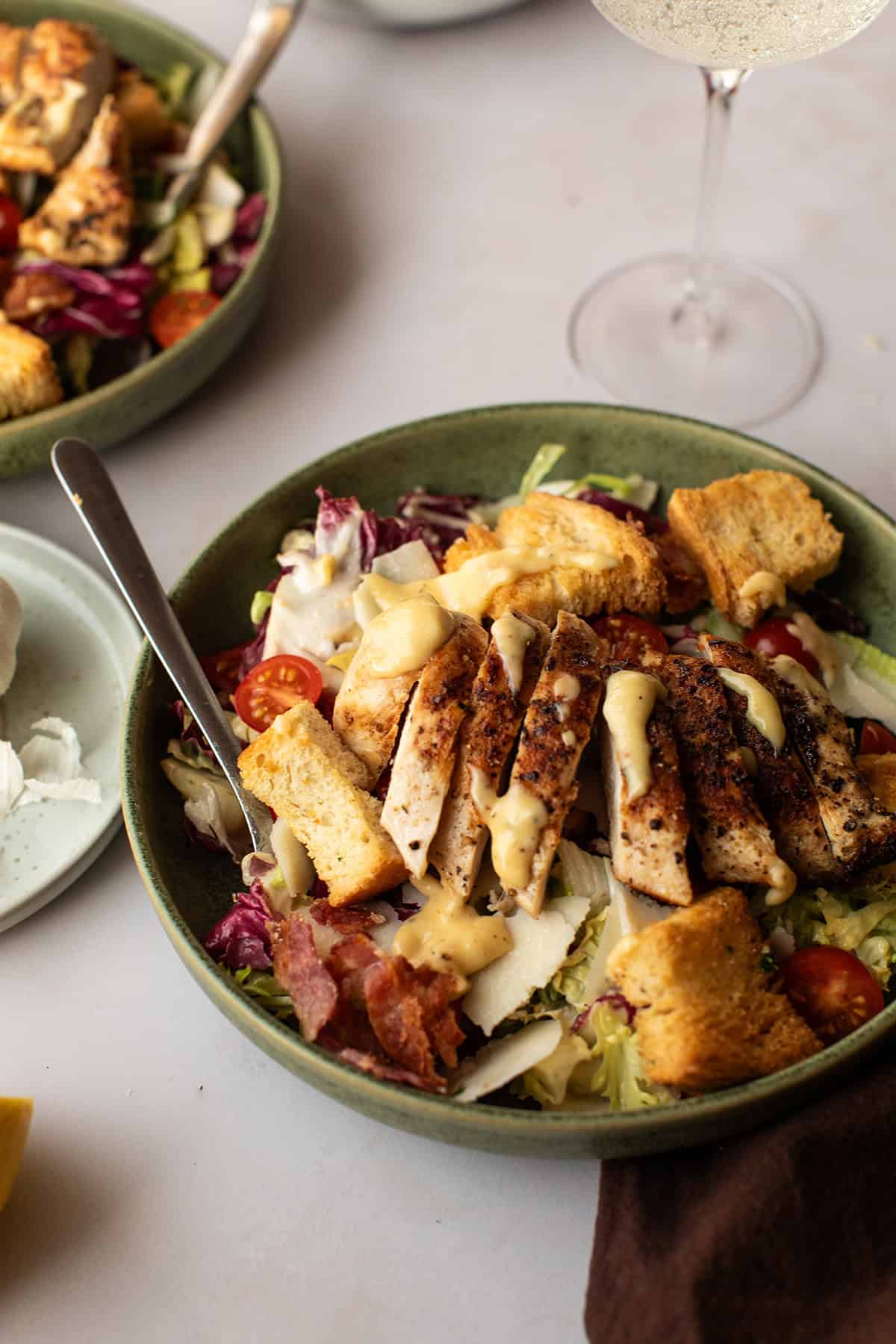 Close-up of a shallow bowl with chicken caesar salad.